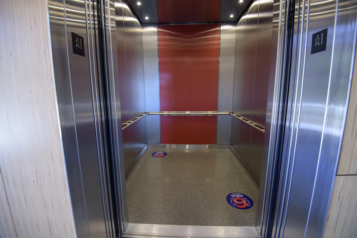 Decals placed on elevator floors mark six feet, helping visualize appropriate distance.