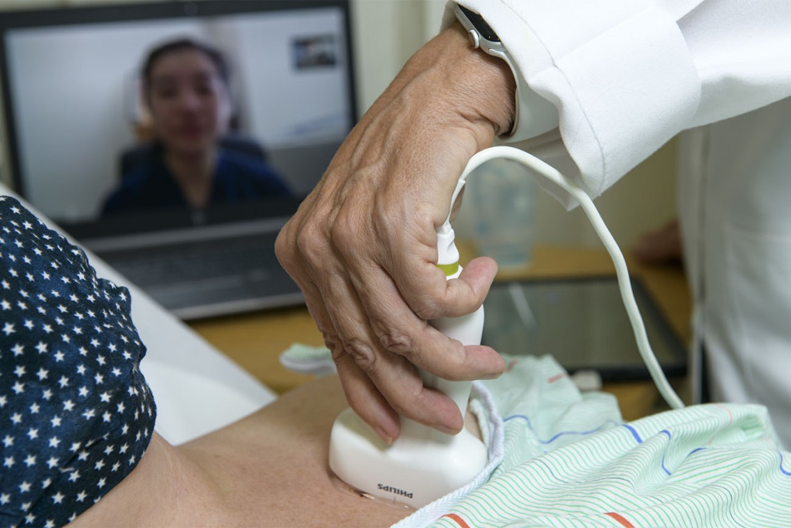 Working with a “standardized patient,” a specialist who portrays patients when health care providers train in new procedures, a doctor learns how to perform bedside lung ultrasound. The physician would wear gloves when treating patients.