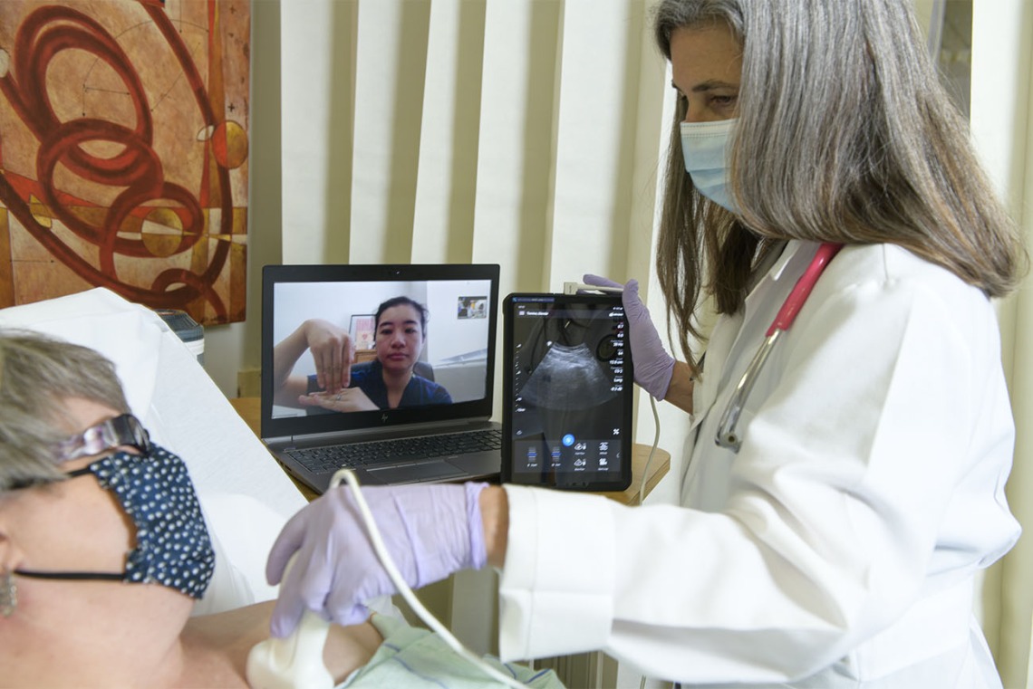 Dr. Elaine Situ-LaCasse (pictured on the laptop) receives a livestream of the exam results and assists in diagnosing a standardized patient during a telehealth training consultation with Julia Brown, MD, emergency department medical director at the Copper Queen Community Hospital in Bisbee, Arizona.