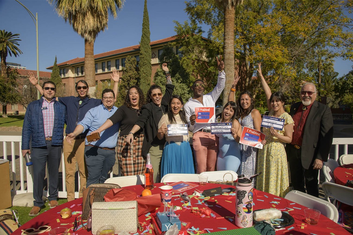 Several third-year medical students along with faculty and staff celebrate with fourth-year students who received their residency matches (holding signs) during the UArizona College of Medicine – Tucson 2022 Match Day event. (From left) Patrick Bryan, Justin Kaye, Ray Larez, Kaloni Philipp, Dinorah Jaime, Naiby Rodriguez, Caylan Moore, Paulina Ramos, Brianna Dolana, Carmen Zaldivar, Carlos Gonzales, MD. 
