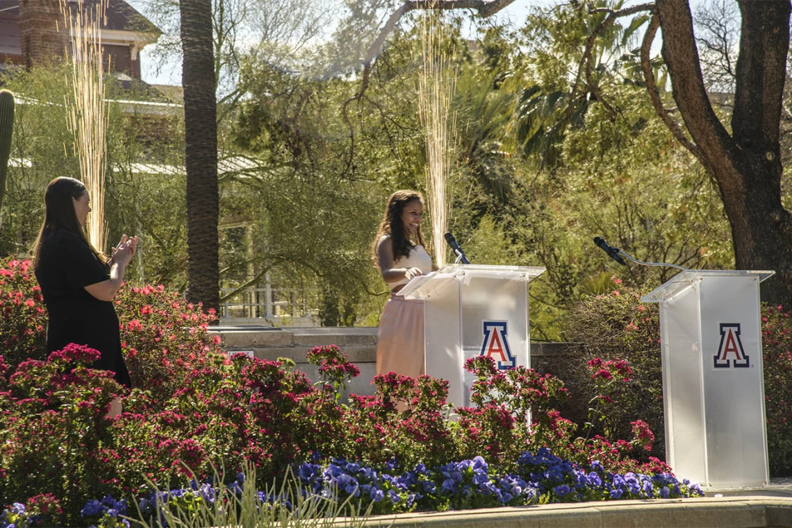 Faith Dickerson announces that she matched for general surgery at the University of Wisconsin as sparks fly behind her at the UArizona College of Medicine – Tucson 2022 Match Day event.