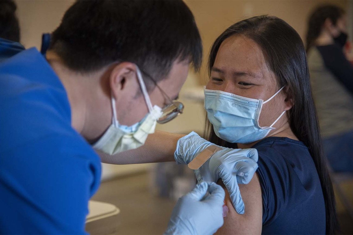 Alvin Wong, DO, a clinical associate professor with the College of Medicine – Phoenix, administers a COVID-19 vaccine to a patient at the community center in Aguila, Arizona, a rural agricultural community west of Phoenix in Maricopa County. 