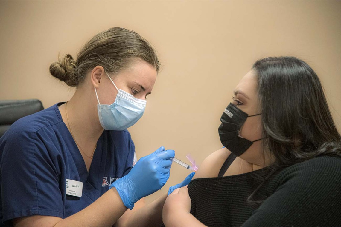 College of Nursing student Valerie Pedersen gives a woman a COVID-19 vaccine at a MOVE UP clinic at the Consulate of Mexico in Douglas hosted by UArizona Health Sciences in partnership with the Cochise County Health Department.