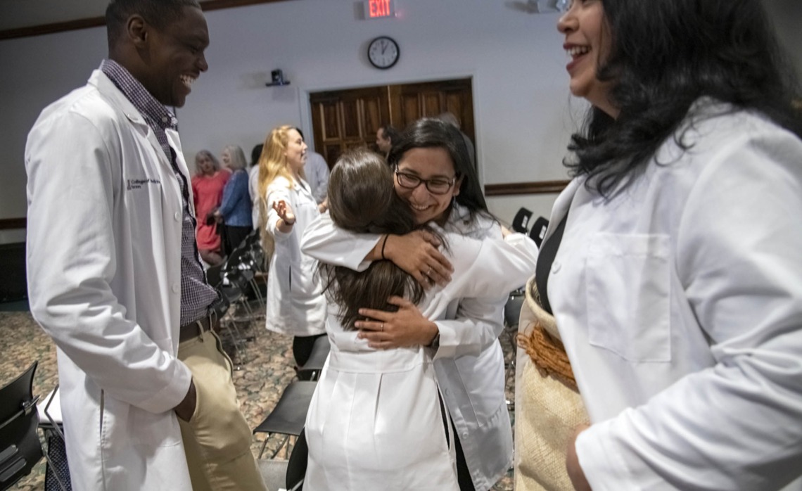 Caylan Moore, left, and Kaloni Philipp, right, watch on as Naiby Rodriguez, center, hugs China Rae Newman after the Primary Care Physician scholarship reception at El Rio in Tucson, Ariz.