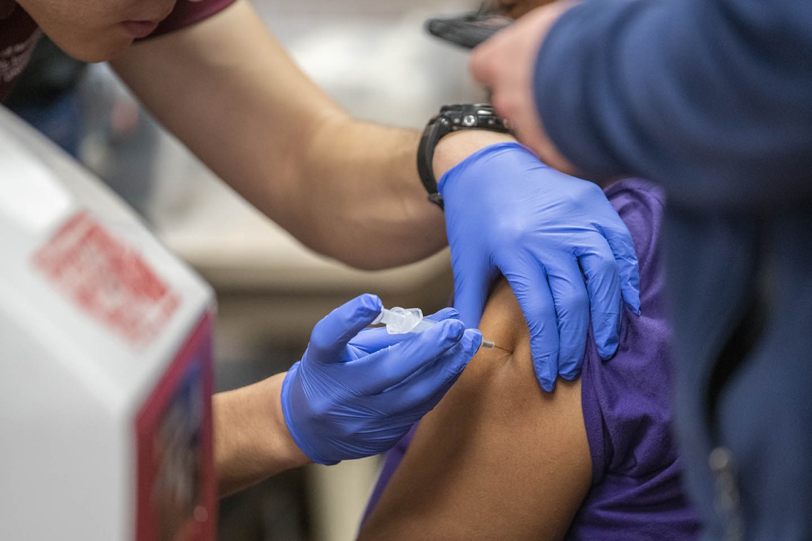 A Street Medicine Phoenix student volunteer administers the flu vaccine to a patient.