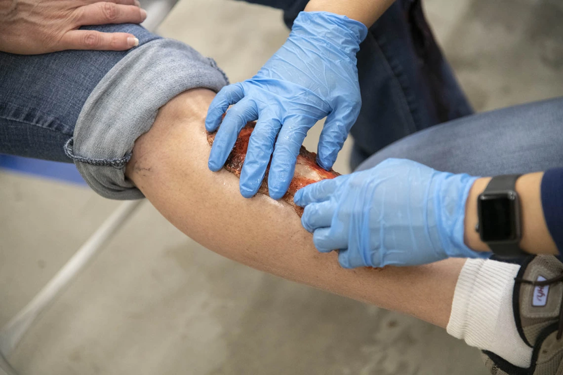 Merryl Lopido, simulation operations specialist for ASTEC, pats down a simulated wound on Helen Ward’s leg. TPD volunteers like Ward will be triaged by first responders based on the severity of their simulated injuries.