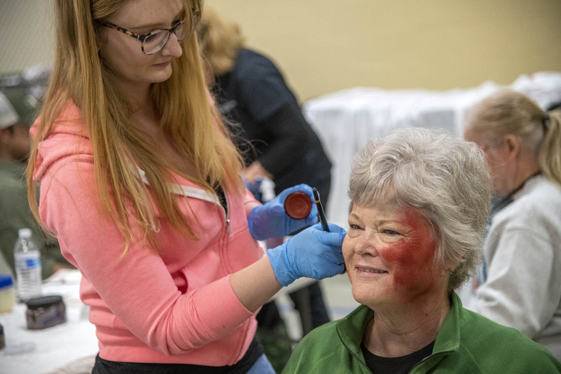 Sadie Keesler, an undergraduate at the University of Arizona College of Science and ASTEC volunteer, creates a burn effect on volunteer Deborah Tilley. Tilley said she was excited to Skype her grandchildren and show them her simulated wounds.