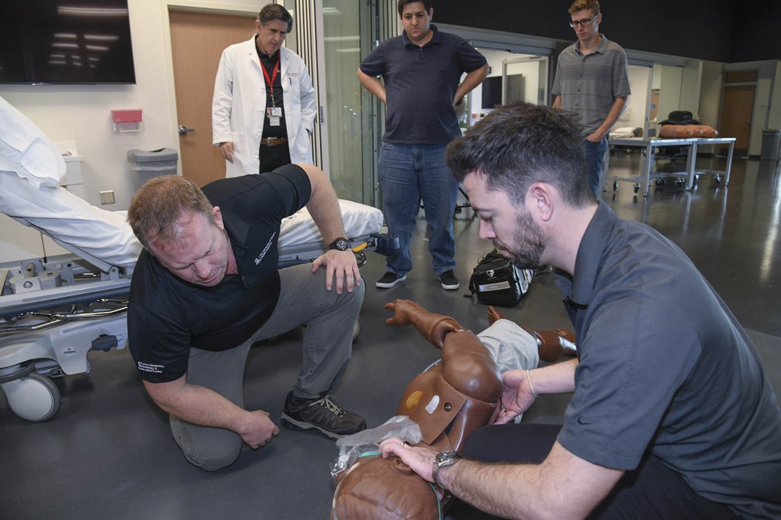 Using lifelike manikins, ASTEC personnel train staff from a local drug rehab facility to treat overdose with naloxone. ASTEC Executive Director Allan Hamilton, MD, FACS, observes from the back left.