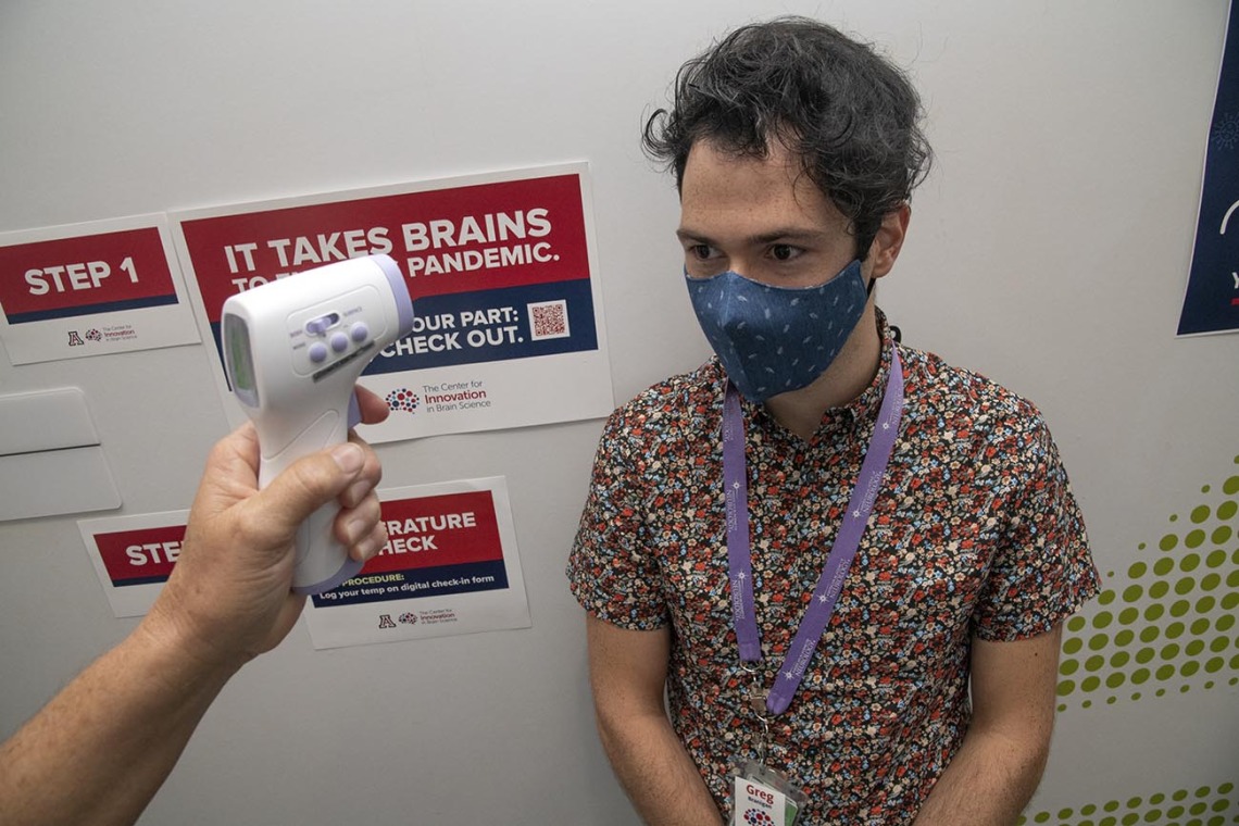 Graduate student Gregory Branigan receives a temperature check outside of the Center for Innovation in Brain Science at Bioscience Research Laboratories. The center implemented COVID-19 screening with daily online health surveys and temperature scans for all faculty, staff and students entering buildings.
