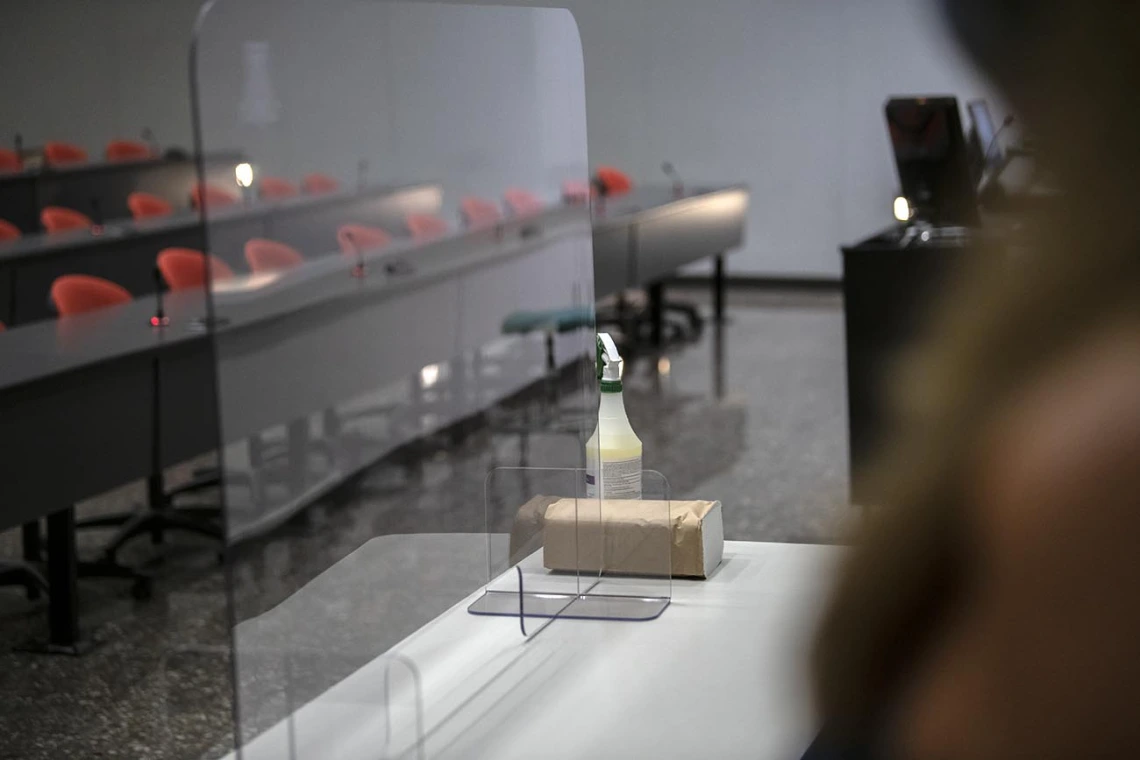 In a large lecture hall, a plastic barrier has been installed to reduce the spread of aerosolized droplets that could carry viruses and other bugs.