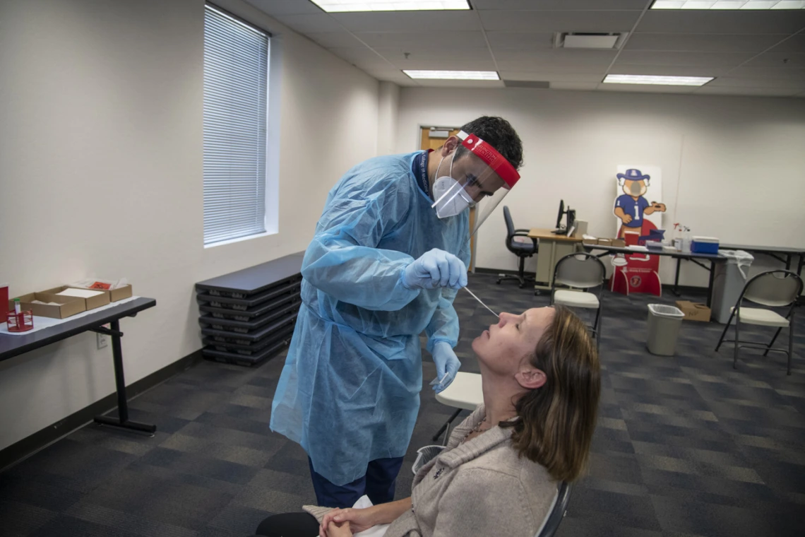 Jeffery Hanna administers a COVID-19 PCR test to UArizona faculty member. Hanna is affiliated with the Mel and Enid Zuckerman College of Public Health in Phoenix. COVID-19 PCR testing was offered at both the Tucson and Phoenix campuses in 2020. A real-time polymerase chain reaction (RT-PCR) test is a molecular diagnostic testing technique that detects the genetic material from the virus. The samples can be collected in a variety of ways, including nasopharyngeal swab and saline gargle.