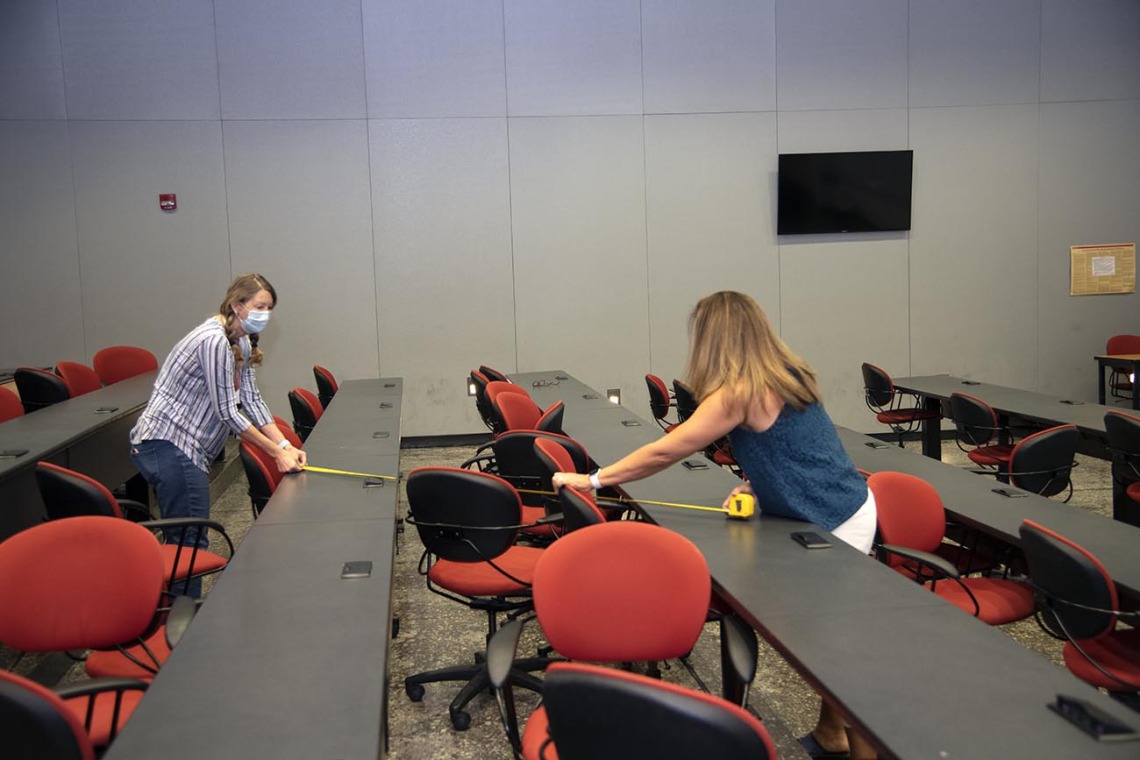 Mary Matthews (left) and Angie Souza (right) of Health Sciences Planning and Facilities measure the distance between desks in a Drachman Hall classroom to ensure students stay six feet apart.