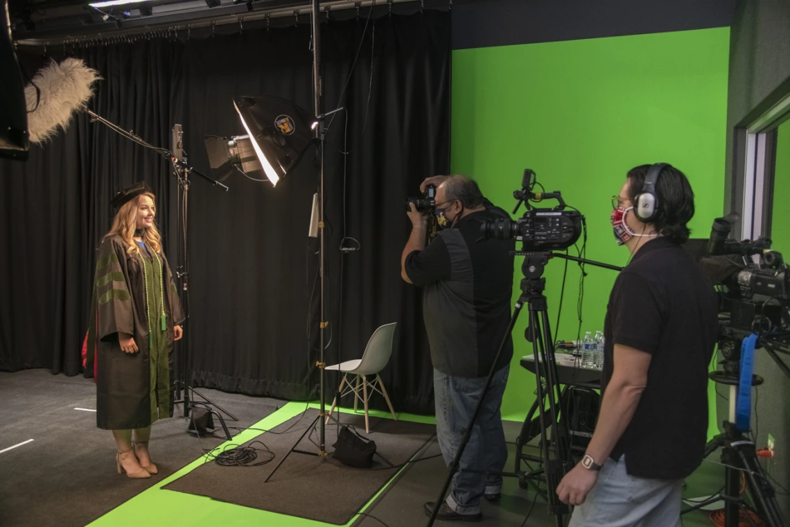 The five Health Sciences colleges planned special ways to mark the rite-of-passage of earning a degree, despite social distancing and stay-at-home orders in May. Medical student Bethany Boczar wears her regalia for a studio shoot in the Health Sciences Innovation Building as Biocommunications photographer Mitchell Masilun and videographer Gilberto Vega film for the College of Medicine – Tucson’s virtual convocation ceremony.