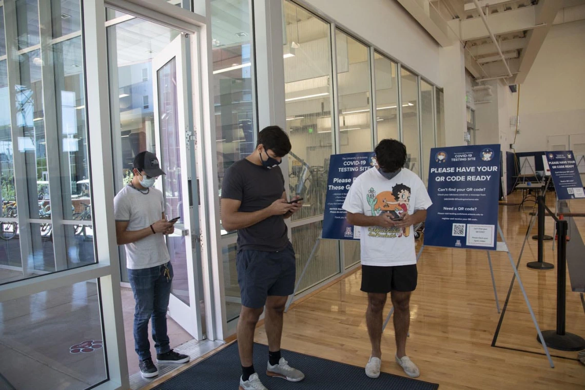 University of Arizona students inside the NorthREC facility, at the Honors Village in Tucson, use their phones to register for COVID-19 antigen testing.