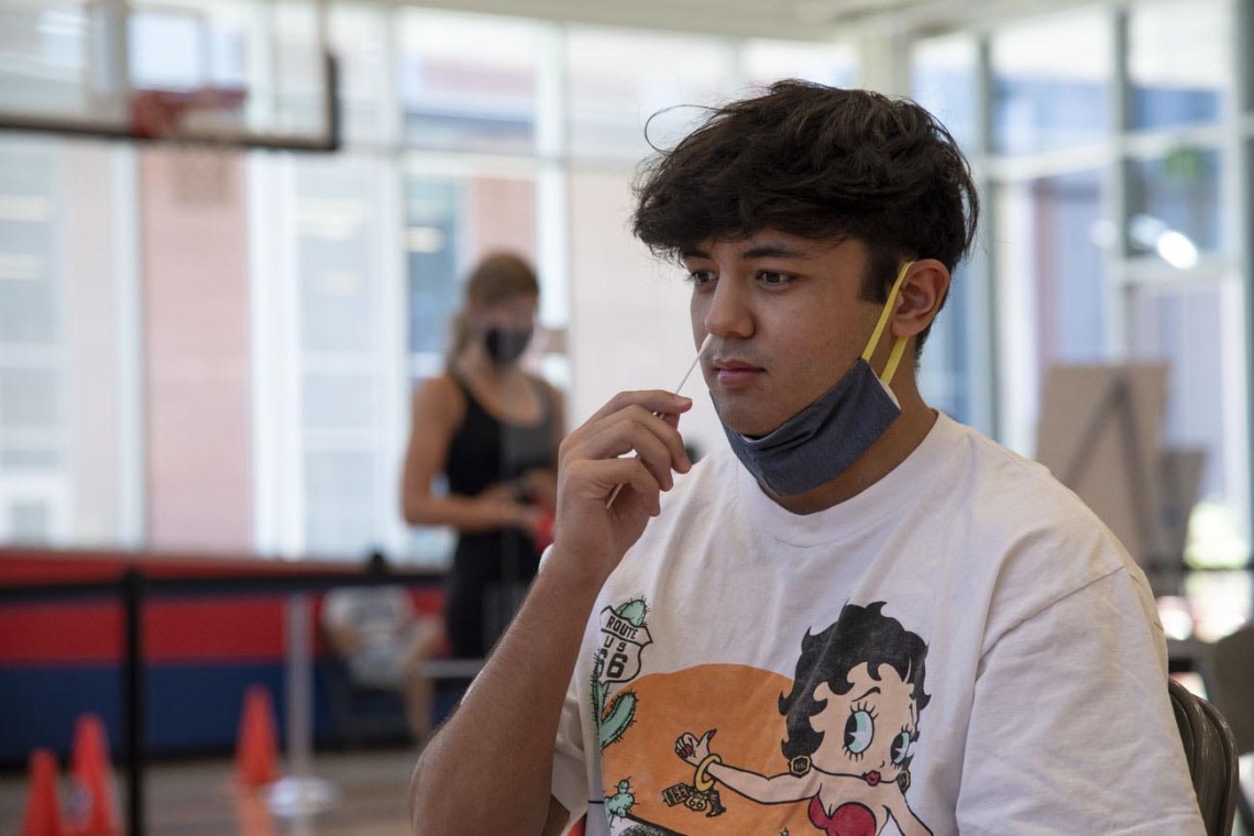 University of Arizona student Mason Young inserts a nasal swab into his nose. The COVID-19 test was required for all dormitory residents and remains available to students and staff.