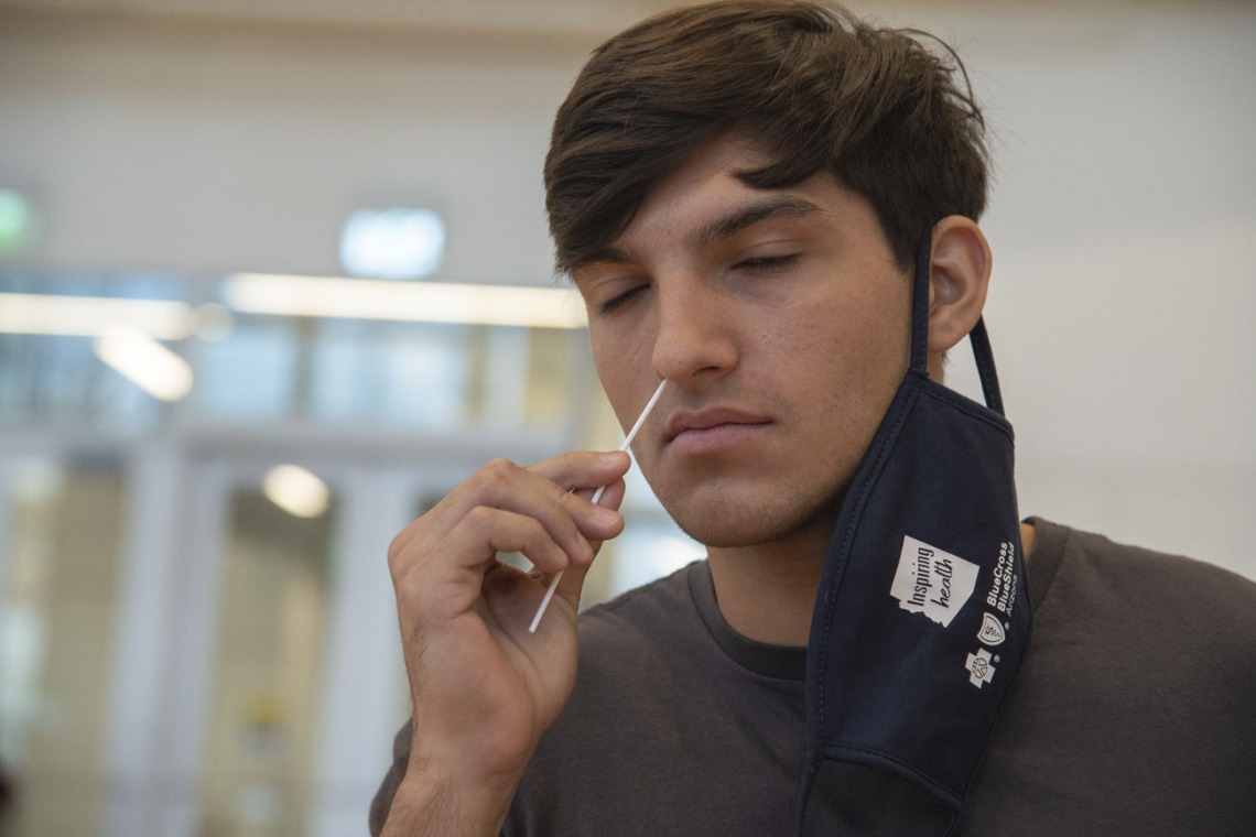 University of Arizona student Heath Zuniga inserts a nasal swab into his nose. The COVID-19 test was required for all dormitory residents prior to moving in to their dorms in August, and remains available to students and staff.