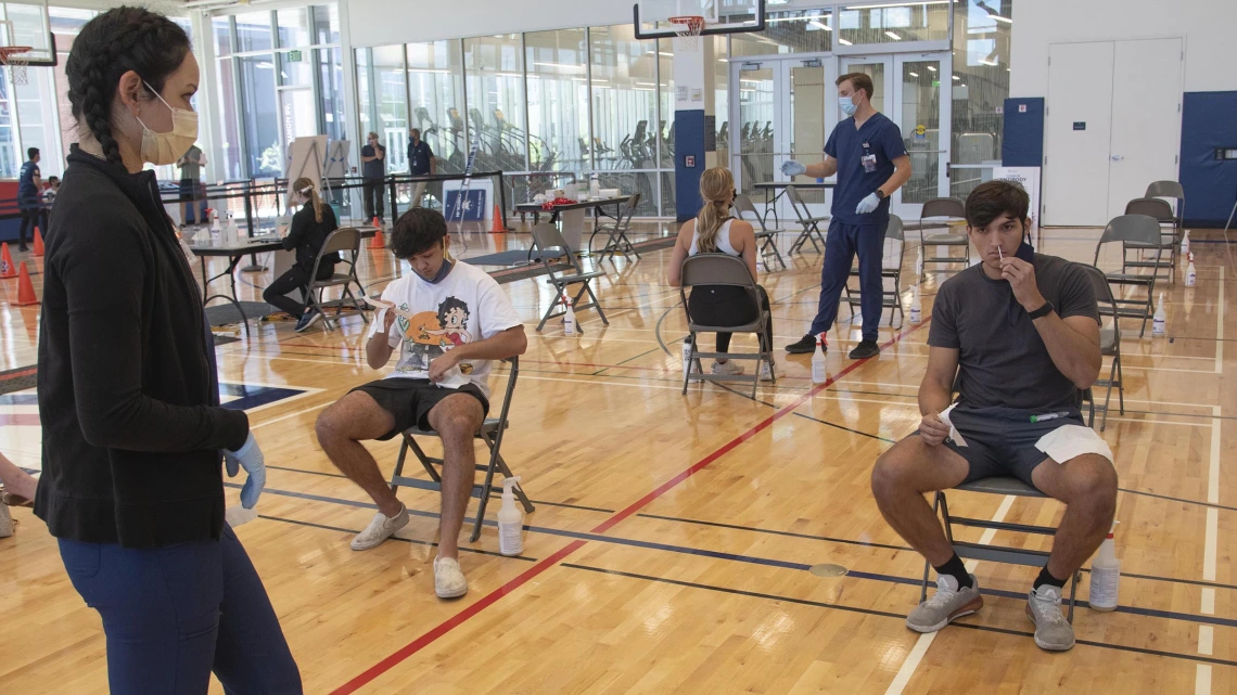 Clinical research coordinator Brenna Abril instructs students in self-administering the nasal swab antigen test at the Recreation and Wellness Center, known as NorthREC, in Tucson.