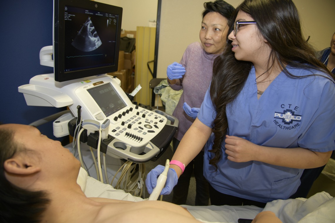 A high school student practices performing an ultrasound on a human heart.