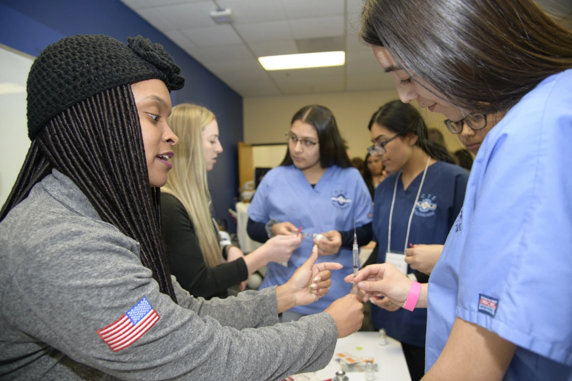 High school students learning about career options in health care visit the nursing booth.