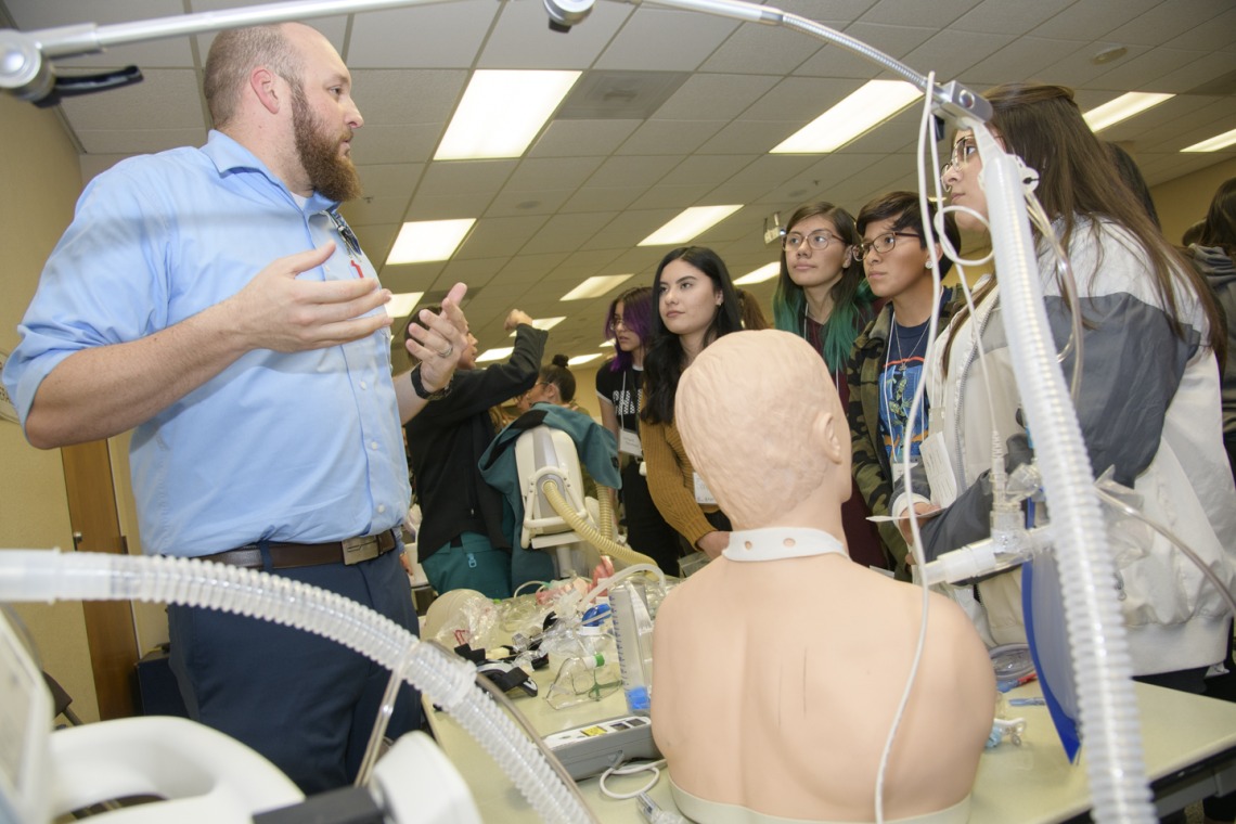 High school students learning about career options in health care gather around the respiratory station.
