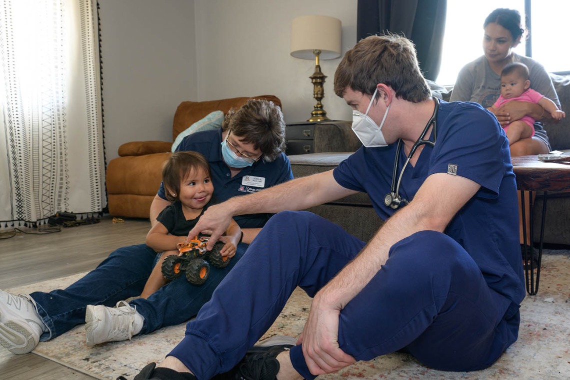 Judith Hunt, MD, and medical student Jeremy Winkleman play with Amara Lopez to set her at ease during a home health visit.
