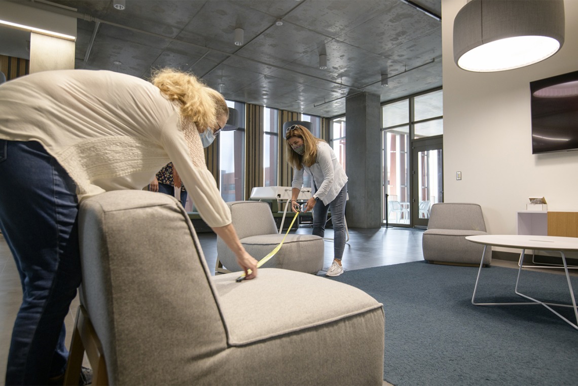 Mary Matthews (left) and Angie Souza (right) of Health Sciences Planning and Facilities measure the distance between chairs in a student lounge in the Health Science Innovation Building to ensure that the placement of furniture facilitates adequate physical distancing.