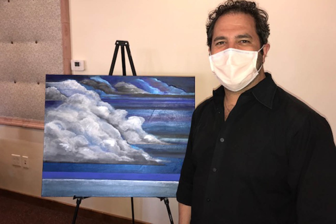 Sean Maiolo, MD, stands with his painting titled "All the Things We Think We Know" at the annual Resident Scholarly Project Program Scholarly Day. Dr. Maiolo said in his artist statement, "The name of the piece holds the key to a place where we can always meet and walk together through that moment in time like friends walking together in the desert when spring blooms because that piece is no longer who I am or what I will always believe.”