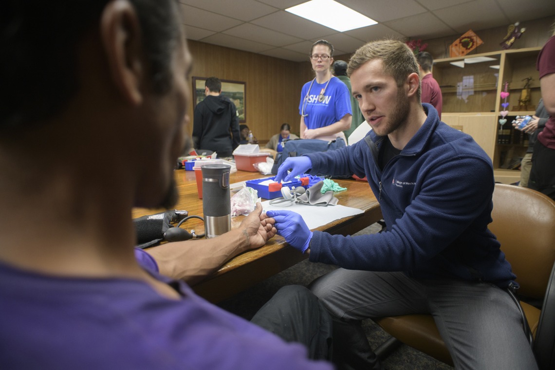 Street Medicine Phoenix co-founder Justin Zeien prepares to test a patient’s blood sugar levels with a finger prick. 
