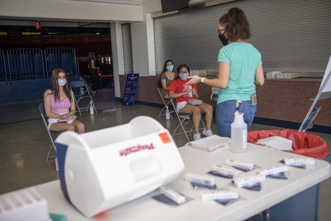 University of Arizona students get tested for COVID-19 by taking a self-administered antigen test at McKale Center in Tucson. 