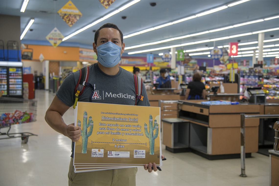 Fourth-year medical student Ricardo Reyes co-led a student-run effort to create Spanish-language social distancing signage. Reyes hangs a sign in a Food City grocery store on South Sixth Avenue in Tucson in May.