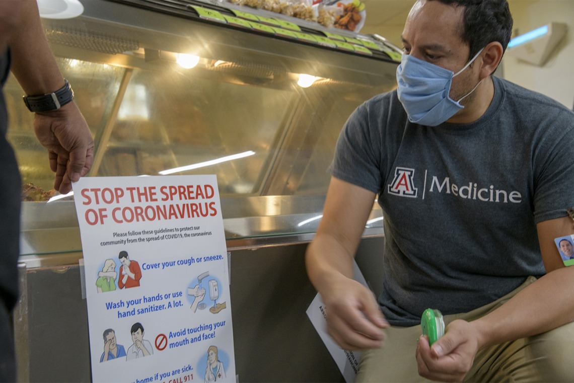 Fourth-year medical student Ricardo Reyes helped create these posters and then hang them in a Tucson grocery store.