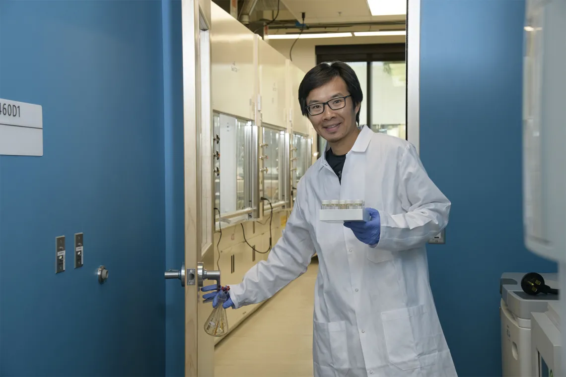 Jun Wang, PhD, walks from a chemistry laboratory into a biology laboratory in the expanded Skaggs research center.