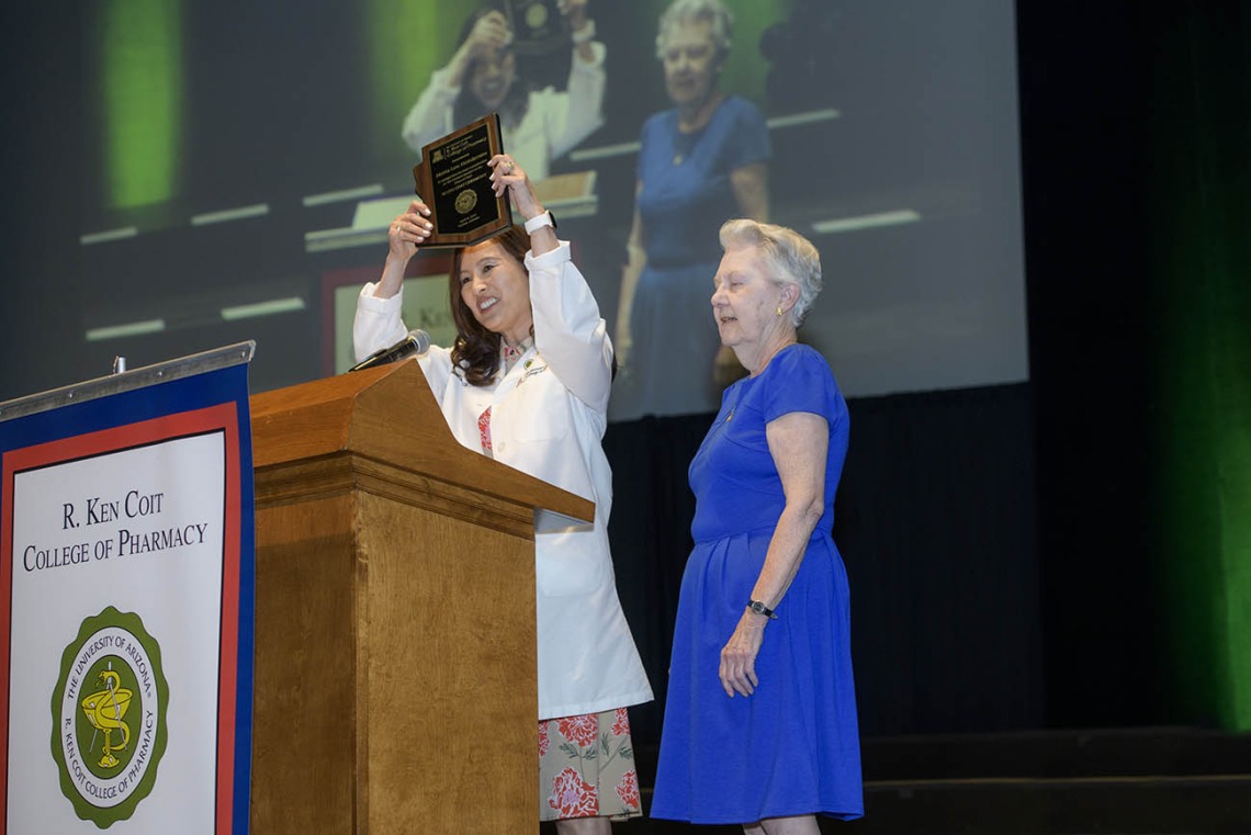 Jeannie K. Lee, PharmD, BCPS, BCGP, FASHP, presents a plaque to guest speaker Metta Lou Henderson, PhD, an alumna, professor of pharmacy emerita and research professor in the Department of Pharmacy Practice at the R. Ken Coit College of Pharmacy. 