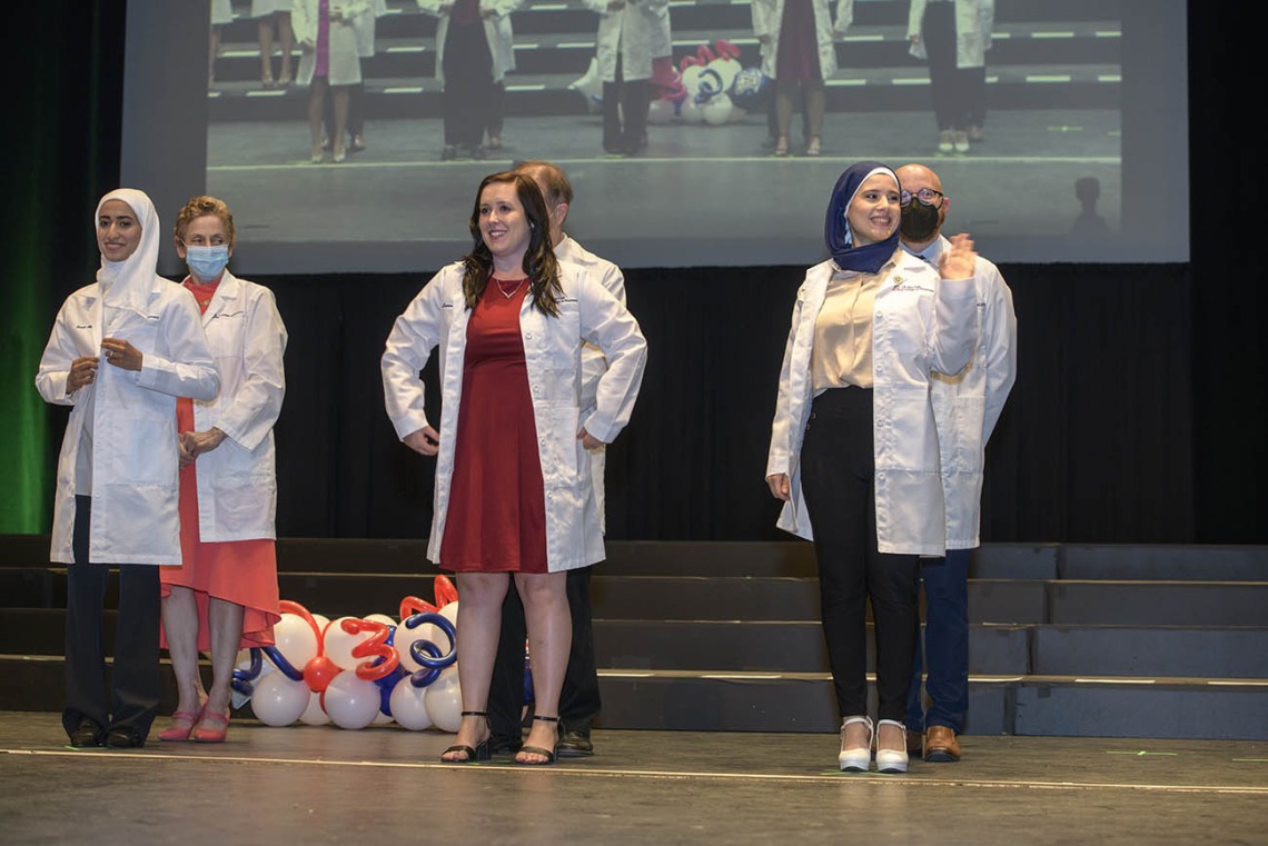 (Front row from left) Sarah Aloqili, Lauren Overholt and Zahraa Ahmed receive their white coats during the R. Ken Coit College of Pharmacy class of 2023 white coat ceremony.
