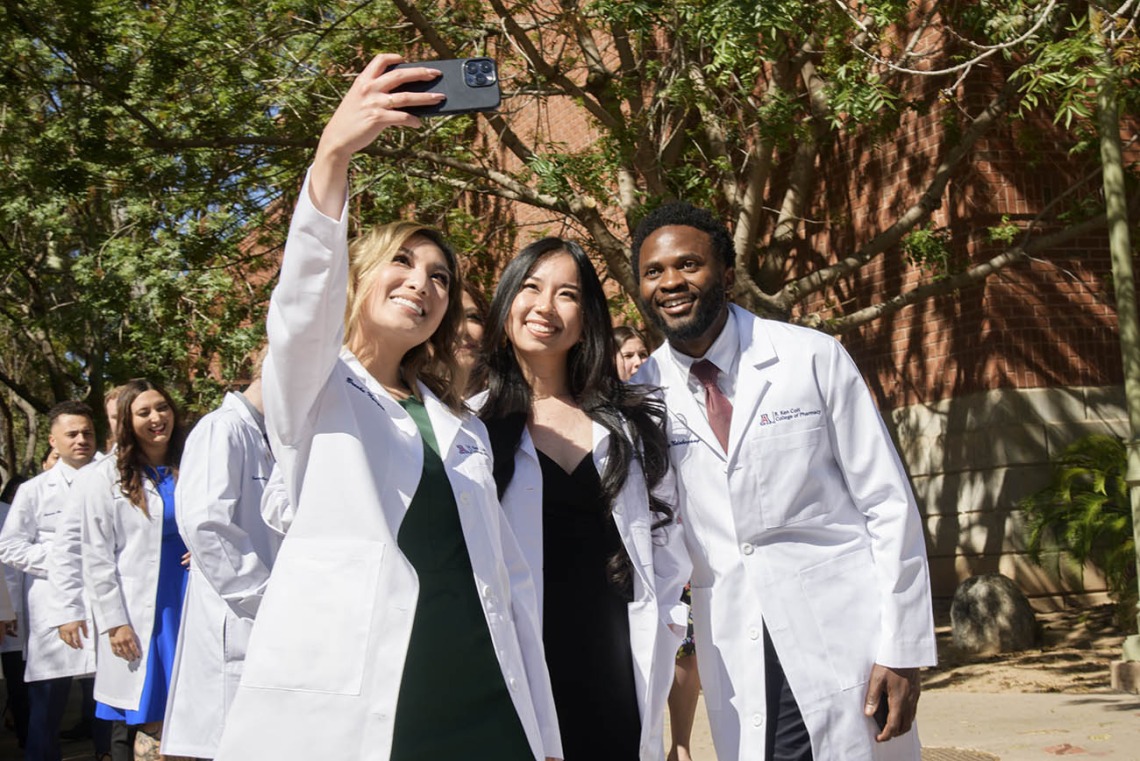 (From left) Brooke Nguyen, Ngoc Nguyen and Anyangatia Ndobegang capture the moment as they leave Centennial Hall after the R. Ken Coit College of Pharmacy class of 2023 white coat ceremony. 