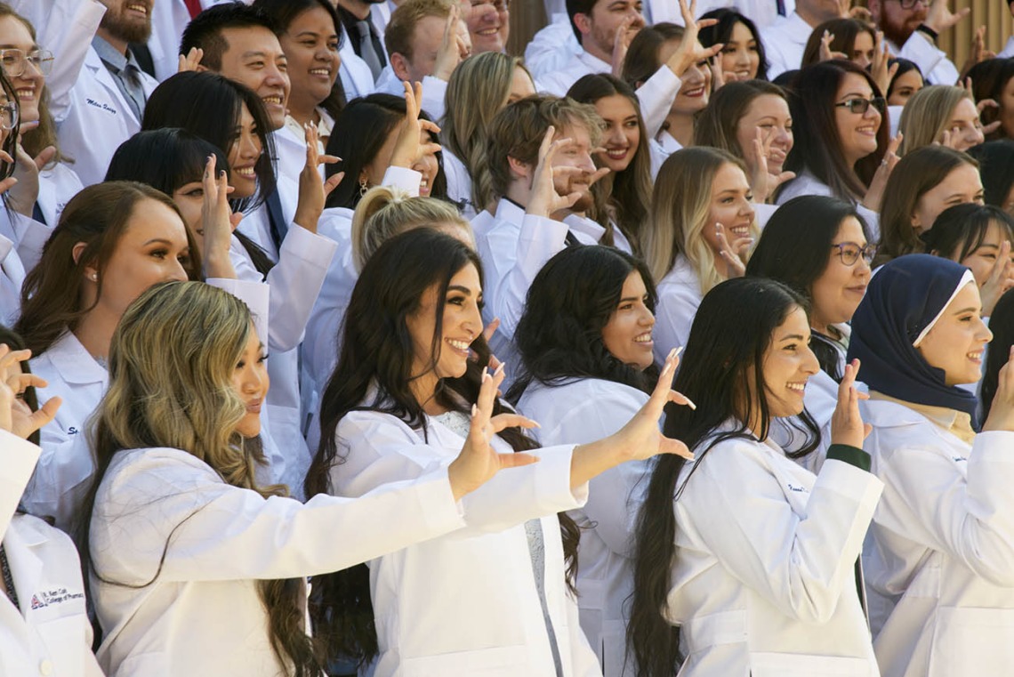 The class of 2023 R. Ken Coit College of Pharmacy students give the Wildcat sign during their class photo after their white coat ceremony at Centennial Hall.