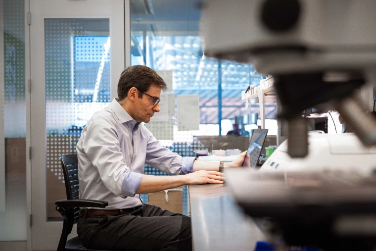 Stefano Guerra, MD, PhD, works with laptop in a lab