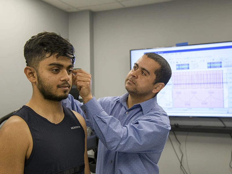 older man attaching sensor to student's head