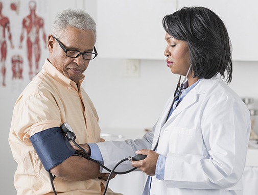 African American doctor checking senior man's blood pressure