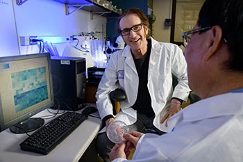 Michael Hammer, PhD (left), and Baowei Chen, PhD, examine cells in which the WIF-1 gene is silenced. (Photo: Kris Hanning)