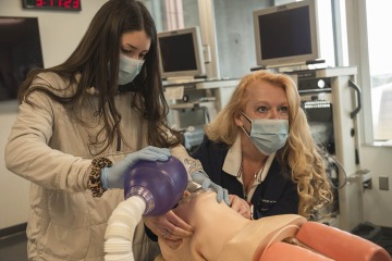First year CRNA student Cameron Wylie practices mask management skills while Kristie Hoch, DNP, CRNA, MS, RRT, demonstrates how a jaw lift will assist in opening the airway.