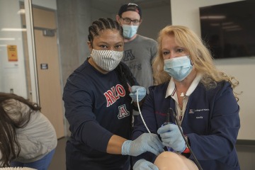 First year CRNA student Sabrena Wells (left) assists Kristie Hoch, DNP, CRNA, MS, RRT, while she demonstrates intubation using a “bougie and GlideScope” technique while Phillip Witte observes.