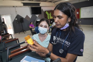 University of Arizona student Chloe Wall (left) watches as College of Nursing graduate Limya Mathew double checks a medication that will go to her patient.
