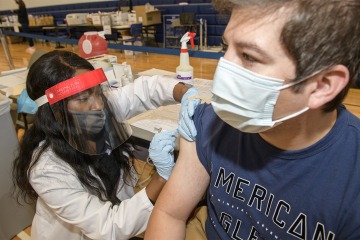 PharmD student Judy Mburu gives a flu shot to Enrique Marquez, a UArizona undergraduate.