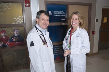 male doctor and female doctor stand in front of Steele Children's Research Center sign