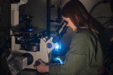 As part of the prototyping and testing stage, Noelle Daigle peers through a fluorescent microscope to inspect a tumor sample.