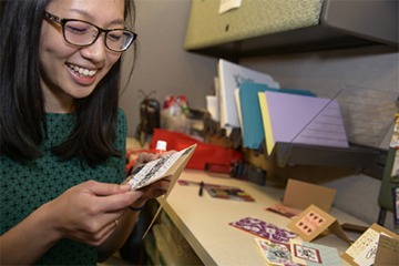Angela Yung, a data manager for LIvES, puts a personal touch on handmade cards sent to ovarian cancer survivors. (Photo: Kris Hanning)