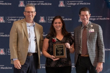 Conrad J. Clemens, MD, MPH, (left) senior associate dean of graduate medical education, and Kevin Moynahan, MD, FACP, (right) vice dean of education, present the Graduate Medical Education Excellence Award to Dr.Tara Carr.