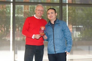 Two men standing and holding glass College of Pharmacy award.