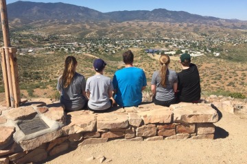 Emma Rautenberg sits with her father and three siblings on a small rock wall atop a hill overlooking the valley below.